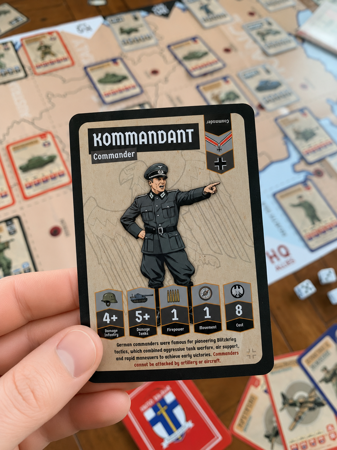 Second world war card 'Kommandant' held over a board game setup with cards and dice.